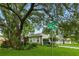A charming house on a corner lot under a canopy of mature oak trees. The address is clearly marked at 4101 Brooke Dr, Valrico, FL 33594