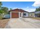 This single-story home features a driveway, brown garage door and white exterior at 4935 42Nd N Pl, St Petersburg, FL 33709