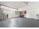 View of a large two-car garage with epoxy floors, overhead lighting, and storage shelves at 5008 Southshore Dr, New Port Richey, FL 34652