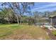 Spacious backyard featuring a screened-in pool area and mature trees, perfect for outdoor activities at 6514 Sunhigh Dr, New Port Richey, FL 34655
