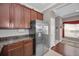 Kitchen with stainless steel refrigerator, wood cabinets, granite countertops, and access to hallway and dining area at 6902 47Th N Ln, Pinellas Park, FL 33781