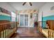 Bedroom featuring two wooden cribs, natural light, laminate flooring, and rainbow wallpaper at 7108 N Howard Ave, Tampa, FL 33604
