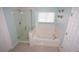 Bright bathroom with a tub and shower combo, white tile surround, and window at 7120 Early Gold Ln, Riverview, FL 33578