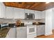 Spacious kitchen with white cabinets, granite countertops, and modern stainless steel appliances at 7337 Glasgow Rd, Weeki Wachee, FL 34613