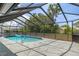 Screened pool with pavers and clear blue water surrounded by lush trees at 7337 Glasgow Rd, Weeki Wachee, FL 34613