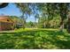Serene backyard with a well-manicured lawn, mature trees, and a glimpse of the home, promising outdoor enjoyment at 7353 Dogwood Cres, Spring Hill, FL 34607