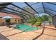 Screened-in pool area featuring a brick pool deck, a spa and lush landscaping creating a private backyard oasis at 7353 Dogwood Cres, Spring Hill, FL 34607