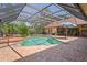 Screened-in pool area featuring a brick pool deck, a spa and lush landscaping creating a private backyard oasis at 7353 Dogwood Cres, Spring Hill, FL 34607