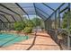Screened-in pool area featuring a brick pool deck, a spa and lush landscaping creating a private backyard oasis at 7353 Dogwood Cres, Spring Hill, FL 34607