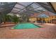 Screened-in pool area featuring a brick pool deck, a spa and lush landscaping creating a private backyard oasis at 7353 Dogwood Cres, Spring Hill, FL 34607