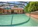 Screened-in pool area featuring a brick pool deck, a spa and lush landscaping creating a private backyard oasis at 7353 Dogwood Cres, Spring Hill, FL 34607