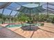 Screened-in pool area featuring a brick pool deck and a blue umbrella over a patio table and chairs at 7353 Dogwood Cres, Spring Hill, FL 34607