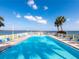 Inviting community pool with sun loungers, palm trees, and serene waterfront views for relaxation and recreation at 7500 Sunshine Skyway S Ln # 201, St Petersburg, FL 33711