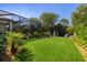 Expansive backyard with lush landscaping, screened enclosure, and a charming playhouse; ideal for outdoor enjoyment at 8434 Dunham Station Dr, Tampa, FL 33647