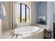 Soaking tub under arched window with elegant decor and natural light at 8434 Dunham Station Dr, Tampa, FL 33647