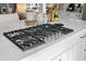 Close-up view of a kitchen island featuring a Hestan cooktop, stone countertops and white cabinets at 8434 Dunham Station Dr, Tampa, FL 33647