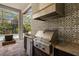 Gourmet outdoor kitchen equipped with stainless steel appliances and beautiful tiled backsplash, perfect for entertaining at 8434 Dunham Station Dr, Tampa, FL 33647