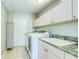 Functional laundry room with ample storage cabinets, a utility sink, and modern washer and dryer at 8529 Regal Ln, Hudson, FL 34667