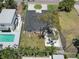 Aerial view showcases the property with a pool, shaded seating, lush landscaping, and a well-maintained roof at 110 8Th St, Belleair Beach, FL 33786