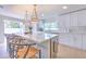 Sun-filled kitchen boasts white cabinetry, stainless steel appliances, a spacious island with seating, and elegant pendant lights at 110 8Th St, Belleair Beach, FL 33786