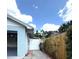 Exterior view from the side yard shows a light blue home, with a brick paver walkway and a partial wood fence at 11303 Hollyglen Dr, Tampa, FL 33624