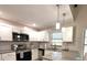 Bright kitchen with white cabinets, granite countertops, stainless steel appliances, and modern pendant lighting at 11303 Hollyglen Dr, Tampa, FL 33624