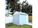 View of the backyard storage shed, painted light blue with a white door at 11303 Hollyglen Dr, Tampa, FL 33624