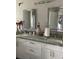 Bright bathroom with double vanity, granite counters, decorative accents and lit vanity mirrors at 11727 Spanish Lake Dr, Tampa, FL 33635