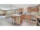 Well-lit kitchen with stainless steel oven, central island with seating and modern laminate flooring at 12502 Tocci Ln, Riverview, FL 33579