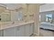 Bathroom featuring double sinks, a large mirror, and an open doorway to an adjacent bedroom at 12950 Pasture Woods Pl, Lithia, FL 33547