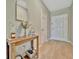 Bright hallway featuring wood floors, a stylish console table with decor, and a view of the front door at 12950 Pasture Woods Pl, Lithia, FL 33547