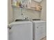 Bright laundry room with white washer, dryer, and overhead shelving for storage at 12950 Pasture Woods Pl, Lithia, FL 33547