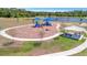Aerial view of a colorful community playground with swings and slides, next to a lake at 12950 Pasture Woods Pl, Lithia, FL 33547