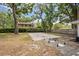 Backyard featuring a sand volleyball court surrounded by mature trees and landscaping at 1407 Jean St, Lutz, FL 33548