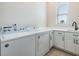 Bright laundry room featuring a white washer and dryer, white cabinets, and countertop space by a window at 16025 Redington Dr, Redington Beach, FL 33708