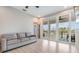 Living room featuring light wood floors with a gray sofa and sliding doors with a balcony at 16025 Redington Dr, Redington Beach, FL 33708