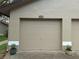 Attached garage with a neutral tone door, accented with planters on either side of the concrete driveway at 1693 Fry Ct, Dunedin, FL 34698