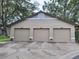 Spacious three car garage, featuring neutral toned doors, concrete driveway, and decorative planters at each entrance at 1693 Fry Ct, Dunedin, FL 34698