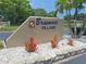 The community sign for Braemoor Village with bromeliads in front and palm trees behind at 1693 Fry Ct, Dunedin, FL 34698