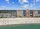Expansive beach view with multiple condominium buildings, blue skies, and ocean waves in this aerial landscape at 17920 Gulf Blvd # 1302, Redington Shores, FL 33708