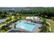Aerial view of a refreshing community pool with ample seating and lush landscaping and tennis courts at 1853 Hovenweep Rd, Wesley Chapel, FL 33543
