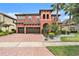 Mediterranean-style home featuring a brick driveway, two-car garage, and well-manicured landscaping with tropical plants at 2608 Calvano Dr, Land O Lakes, FL 34639