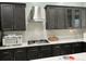 Modern kitchen showcases a stainless steel range hood, gas cooktop, dark cabinets, and elegant white quartz backsplash at 29042 Rivergate Run, Wesley Chapel, FL 33543