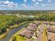 A picturesque aerial captures homes next to a serene lake, complemented by lush green landscapes and blue skies at 30327 Lettingwell Cir, Wesley Chapel, FL 33543