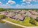 An aerial view showcases the community's tranquil lake, lush landscaping, and well-spaced homes with screened patios at 30327 Lettingwell Cir, Wesley Chapel, FL 33543