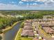 An aerial view reveals homes situated alongside a lake, surrounded by abundant lush greenery and a clear sky at 30327 Lettingwell Cir, Wesley Chapel, FL 33543