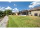 A view of the home's backyard featuring a pond, manicured lawn, and covered patio at 30327 Lettingwell Cir, Wesley Chapel, FL 33543