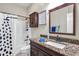 Cozy bathroom features a granite countertop, dark wood vanity, and shower with decorative curtain at 30327 Lettingwell Cir, Wesley Chapel, FL 33543