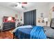 Comfortable bedroom with dark wood floors, black furniture, and a TV displaying a cozy fireplace at 30327 Lettingwell Cir, Wesley Chapel, FL 33543