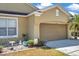 Home featuring a brown garage door, a bird bath, lawn decorations, and a sunny sky at 30327 Lettingwell Cir, Wesley Chapel, FL 33543